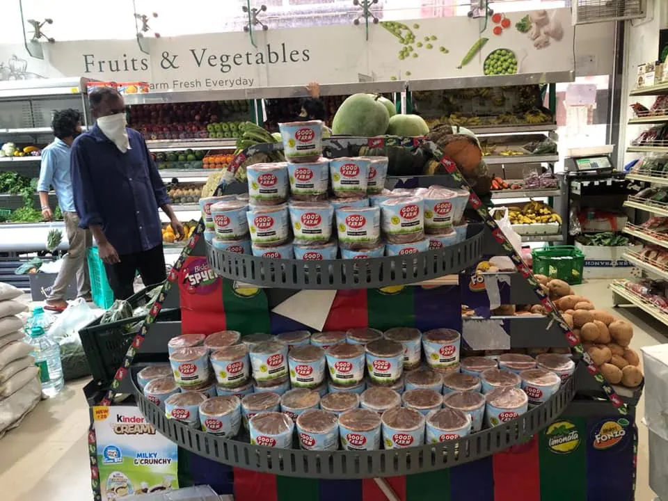 A supermarket display stacked with Good Farm jaggery packs beside the fruit and vegetable section